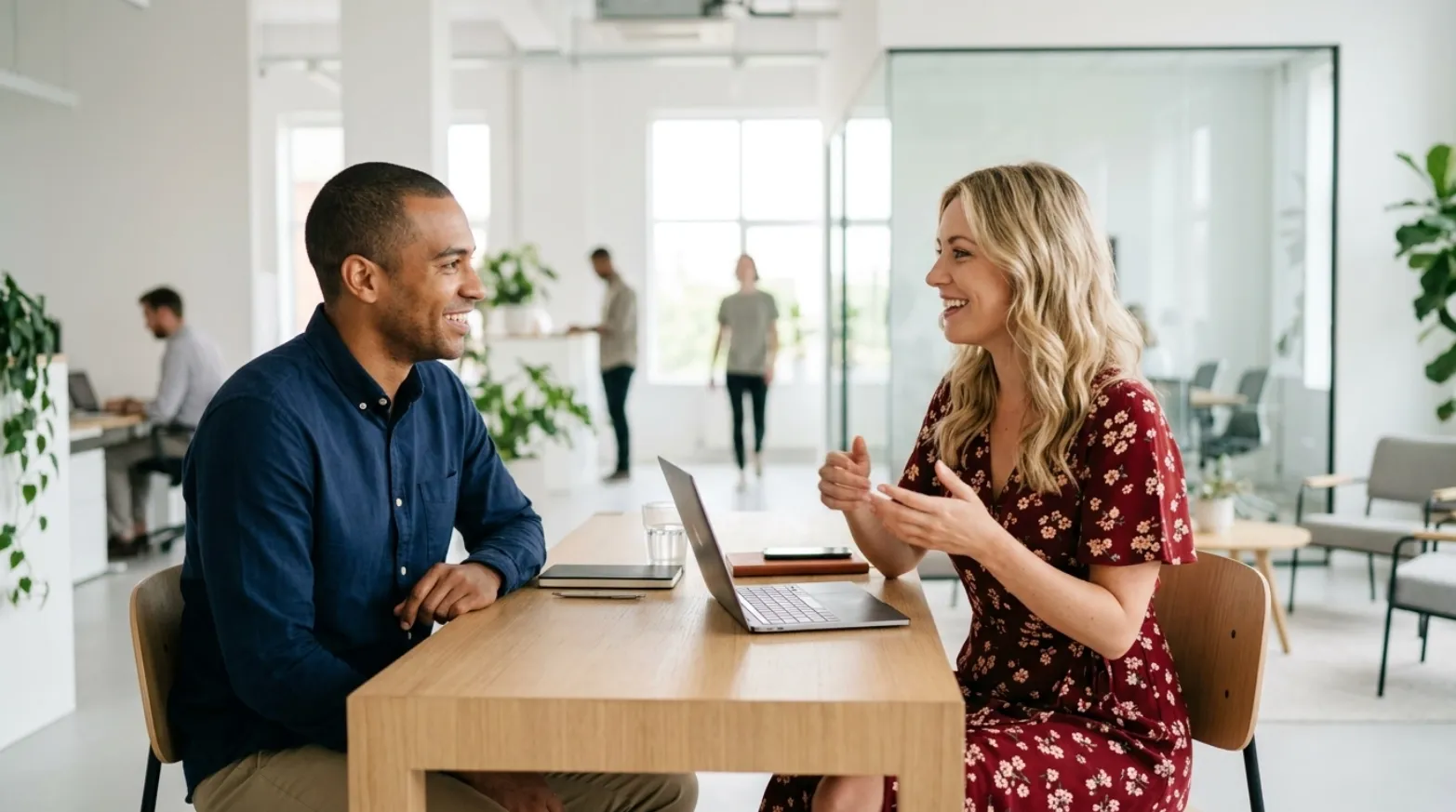 Two colleagues talking across a table in a bright office